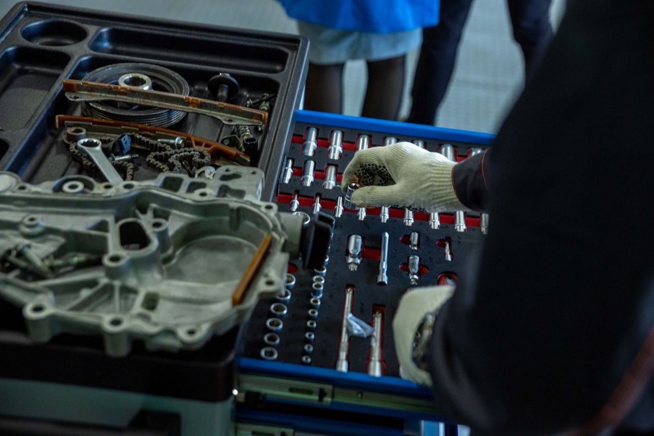 Services A mechanic in gloves organizing engine parts and tools in a workshop setting.