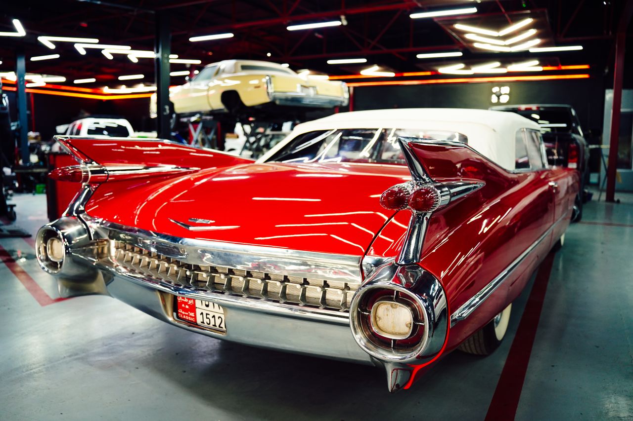 About Vintage red Cadillac parked in a sleek, modern garage setting with visible license plate details.