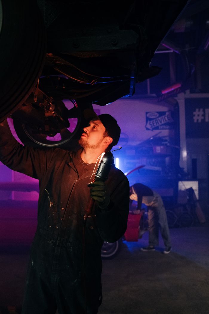 About A mechanic inspects a car in a neon-lit garage, highlighting modern repair work.